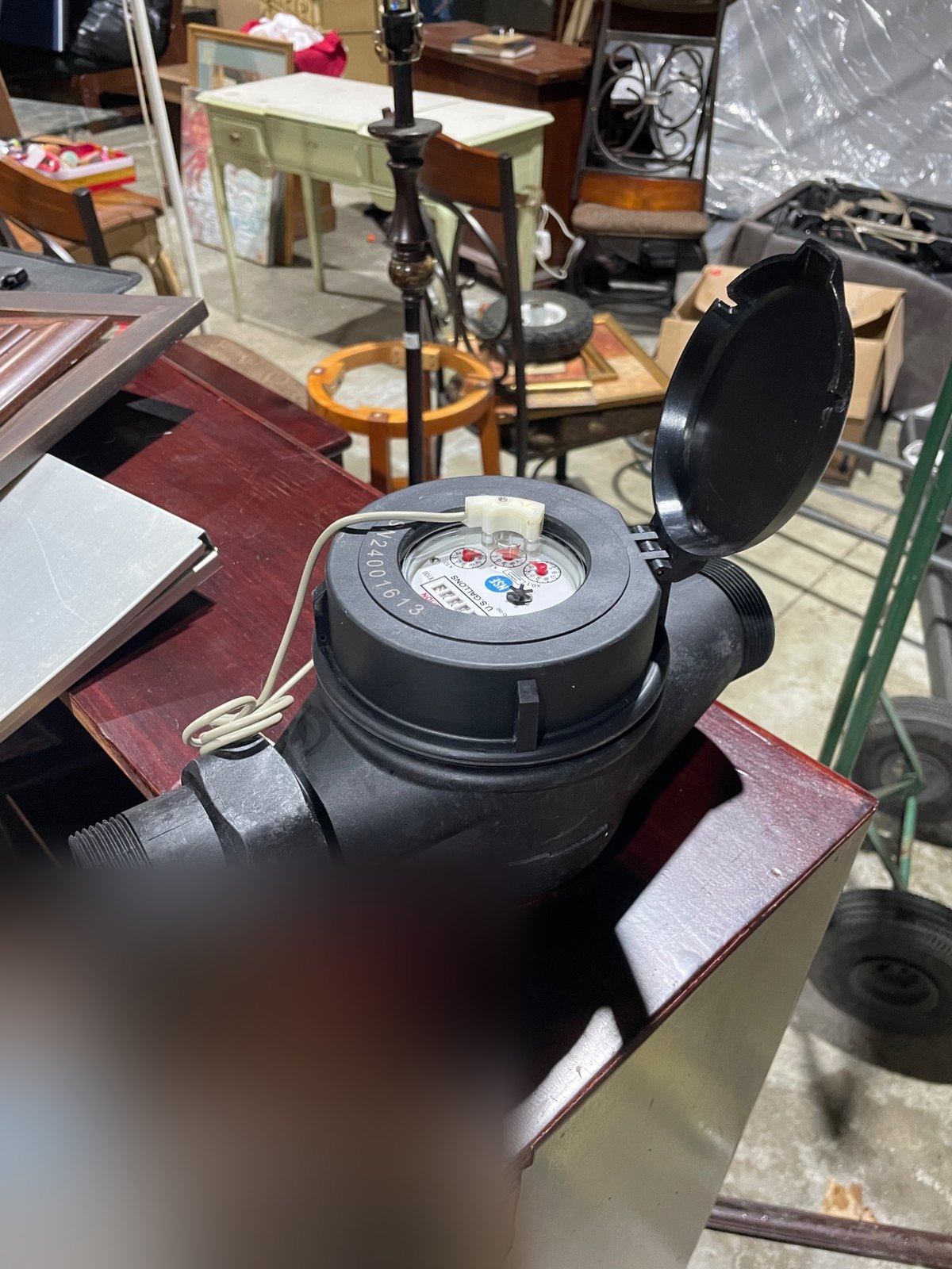 A new water meter for one suite of a commercial building, its lid open, ready to be installed
